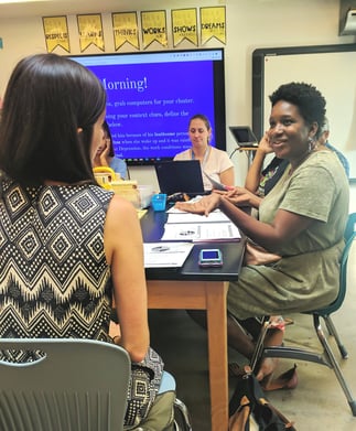 The group of educators smile as they collaborate with one another.
