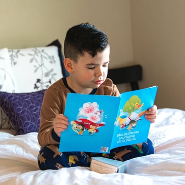 Graphic of a young student reading a picture book on his bed.