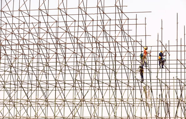 Three people on a large scaffold fixing something