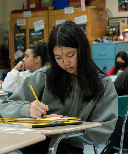 a student writing on a notebook at their desk